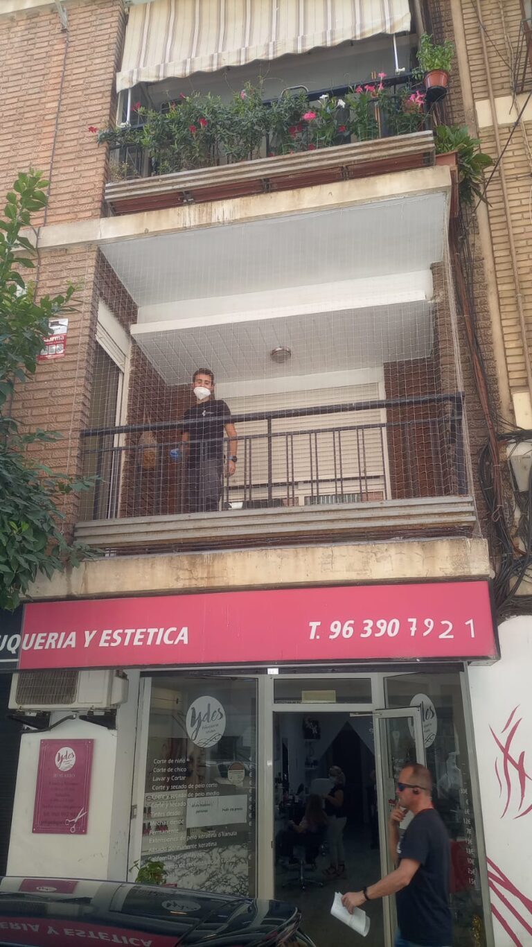 Instalador trabajando en la red de un balcón en fachada